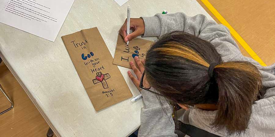children writing positive notes on paper bags